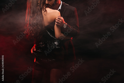 cropped view of passionate couple hugging in red smoky room photo