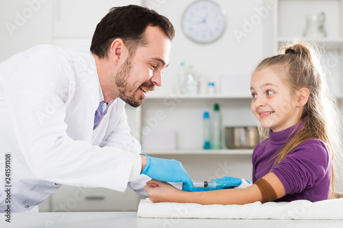 Male doctor injecting little patient