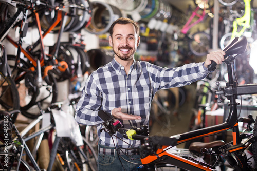man checks bicycle handlebar in shop when choosing bike