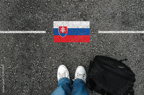 Wallpaper Mural a man with a shoes and backpack is standing on asphalt next to flag of Slovakia