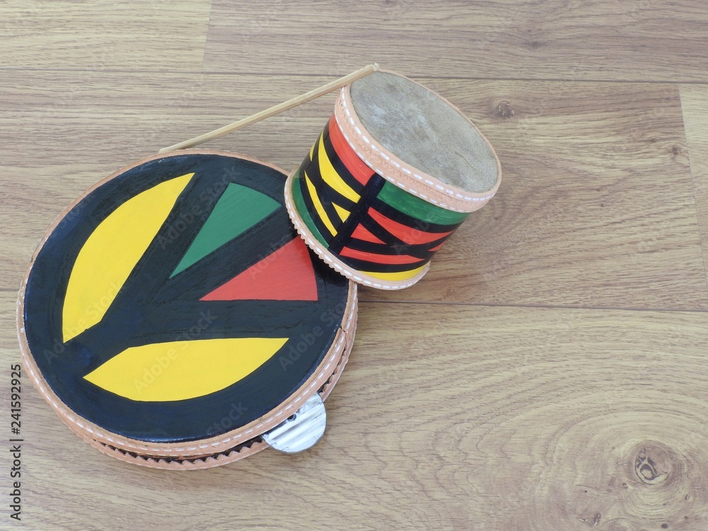 Two colorful Brazilian handmade percussion instruments: pandeiro (tambourine)  and a small drum with drumstick. They are used to play samba and at  carnival. The tambourine has the peace symbol. Stock Photo