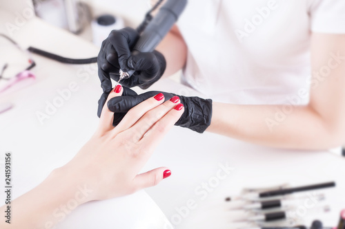 Manicurist  nail artist handles nails with manicure milling cutter. Beauty service  nail salon  health care and cosmetics.