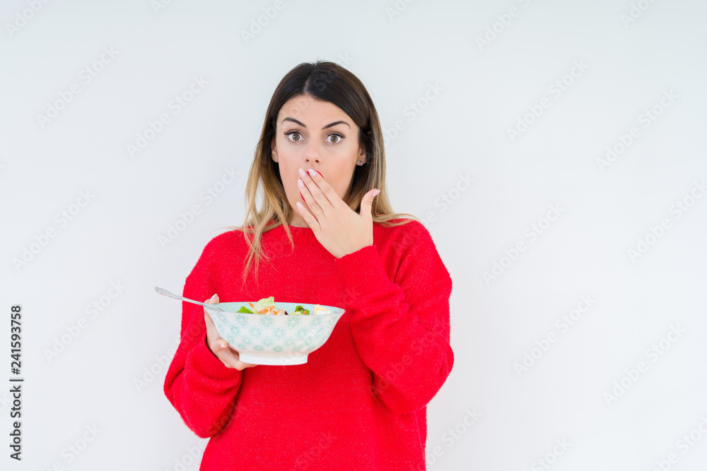 Young woman eating fresh healthy salad over isolated background cover mouth with hand shocked with shame for mistake, expression of fear, scared in silence, secret concept Young woman eating fresh healthy salad over isolated background cover mouth with hand shocked with shame for mistake, expression of fear, scared in silence, secret concept