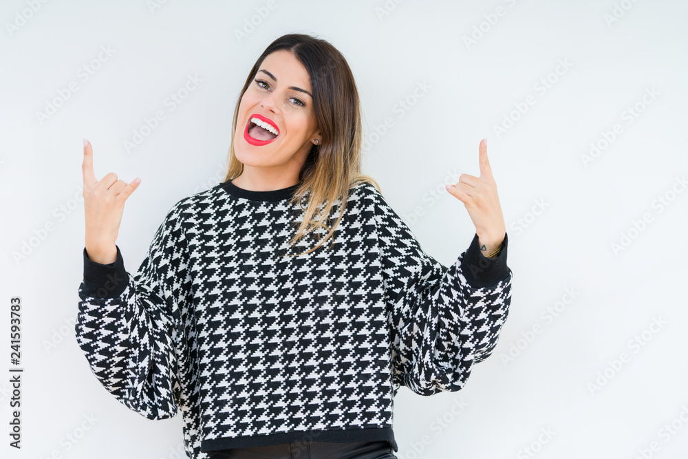 Young woman wearing casual sweater over isolated background shouting with crazy expression doing rock symbol with hands up. Music star. Heavy concept. Young woman wearing casual sweater over isolated background shouting with crazy expression doing rock symbol with hands up. Music star. Heavy concept.