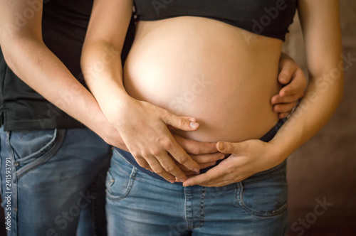 A pregnant woman and the father of the child hold the belly. Maternity, in anticipation of the baby, family. © Evgeniya