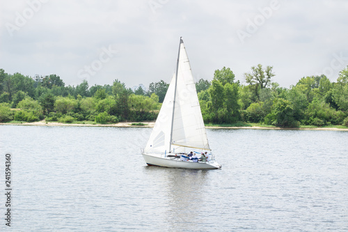 Sailboat yacht team sailing with full sails on river lake
