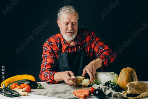 old friendly man is giving food to chickens. isolated black background, studio shot. farmer fatting up birds photo