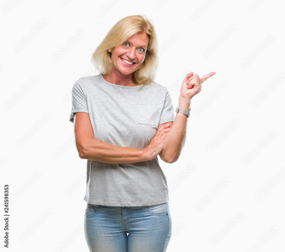 Middle age blonde woman over isolated background with a big smile on face, pointing with hand and finger to the side looking at the camera. Middle age blonde woman over isolated background with a big smile on face, pointing with hand and finger to the side looking at the camera.
