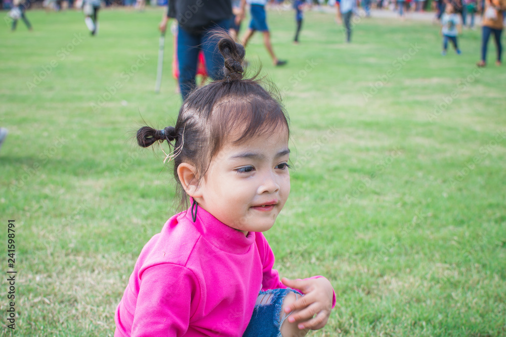 happy little girl sitting on green grass and playing in the park. soft focus. happy little girl sitting on green grass and playing in the park. soft focus.
