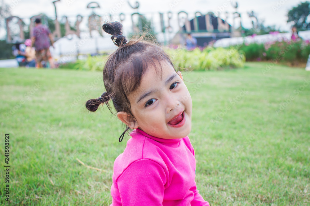 happy little girl sitting on green grass and playing in the park. soft focus. happy little girl sitting on green grass and playing in the park. soft focus.