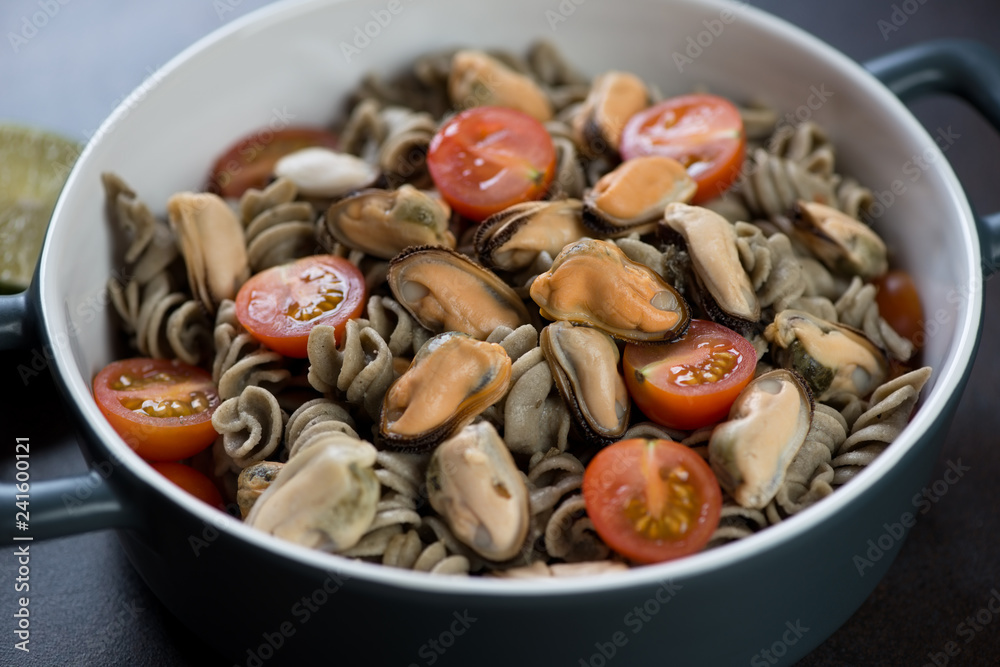 Bowl of hemp flour pasta served with mussels and cherry tomatoes, selective focus, studio shot Bowl of hemp flour pasta served with mussels and cherry tomatoes, selective focus, studio shot