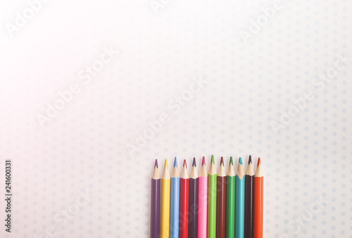 Color pencils lying on cute spotted background with dots. Back to school concept. Colorful art studying and painting process. Drawing with pencils. Copy space place for postcard wish.