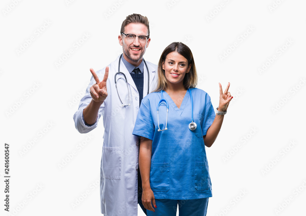 Young couple of doctor and surgeon over isolated background smiling with happy face winking at the camera doing victory sign. Number two. Young couple of doctor and surgeon over isolated background smiling with happy face winking at the camera doing victory sign. Number two.