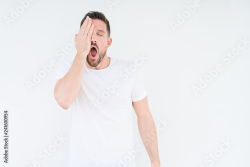 Young handsome man wearing casual white t-shirt over isolated background Yawning tired covering half face, eye and mouth with hand. Face hurts in pain.