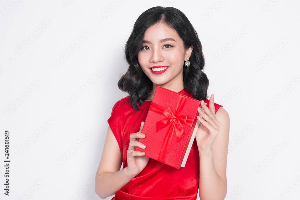 Beautiful Asian girl holding a present in her hands and smiling against the white background Beautiful Asian girl holding a present in her hands and smiling against the white background