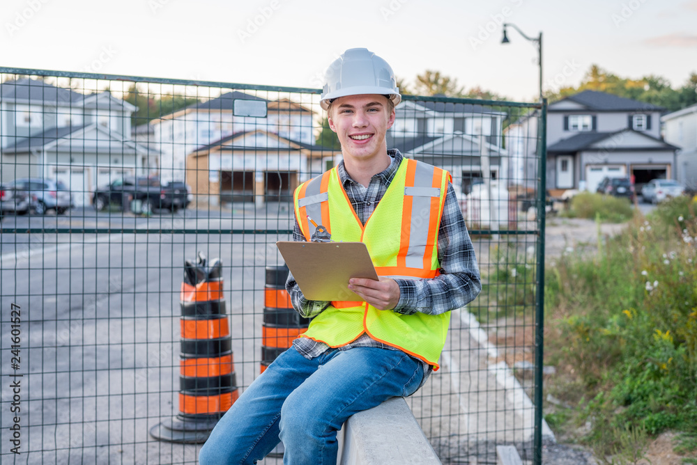 Happy young construction worker wearing safety gear and holding a clipboard. Happy young construction worker wearing safety gear and holding a clipboard.