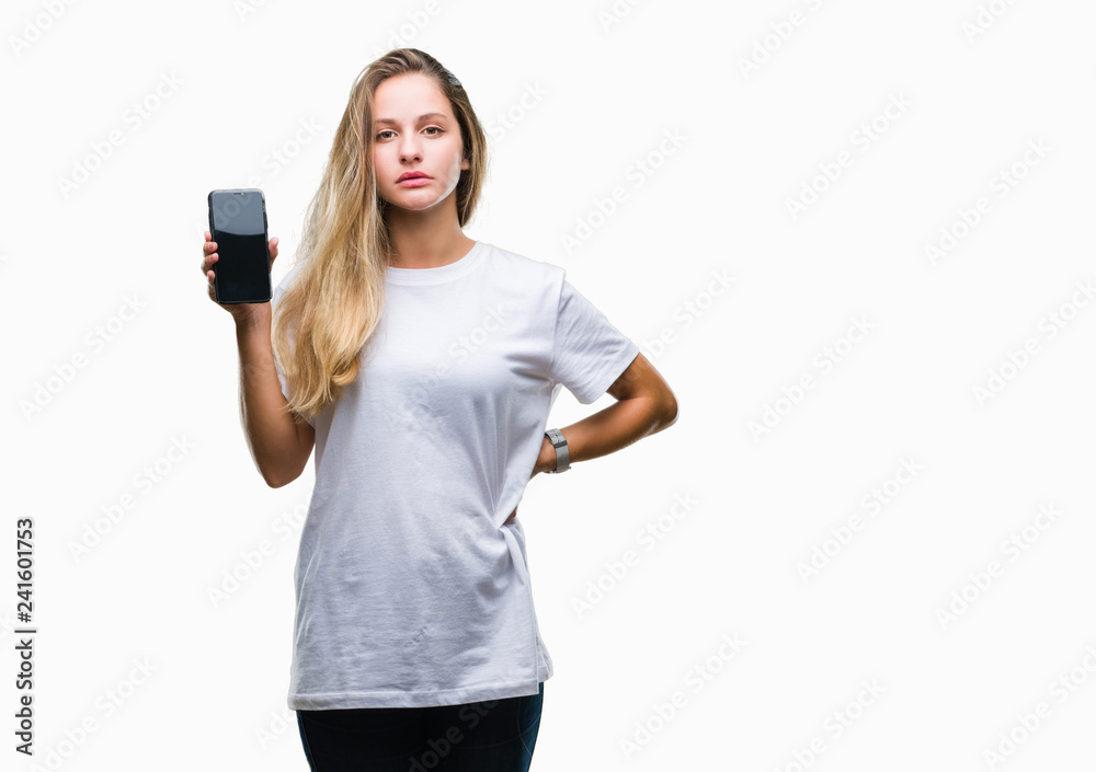 Young beautiful blonde woman showing screen of smartphone over isolated background with a confident expression on smart face thinking serious Young beautiful blonde woman showing screen of smartphone over isolated background with a confident expression on smart face thinking serious