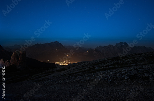 night panorama of the Dolomites mountains with a small illuminated village