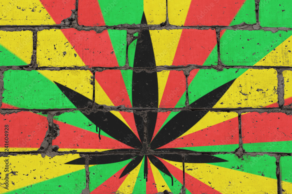 Fototapeta premium Cannabis leaf depicted on brick colored wall in style of rasta. Graffiti street art spray drawing on stencil.