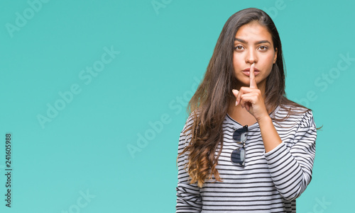 Young beautiful arab woman wearing sunglasses over isolated background asking to be quiet with finger on lips. Silence and secret concept.