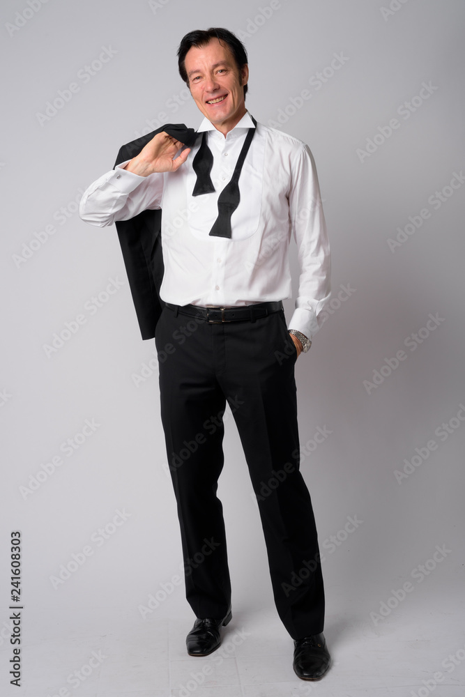 Full body shot of happy mature handsome businessman carrying jacket over shoulder Full body shot of happy mature handsome businessman carrying jacket over shoulder