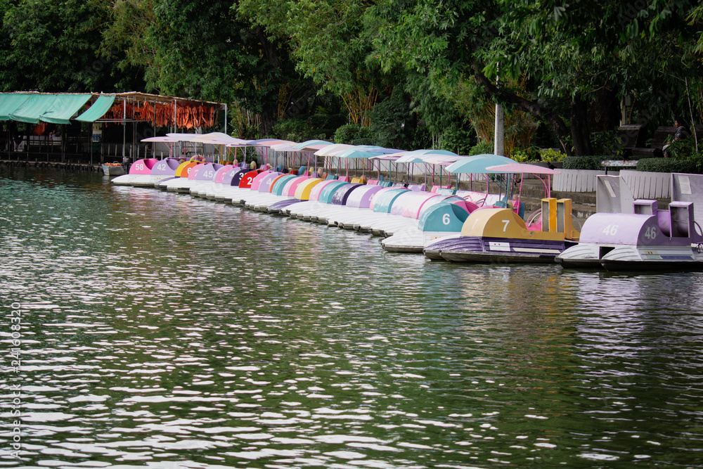 Fototapeta premium Colorful pedal Rental Boats in the public parked on the lake at Khao Din Zoo in Thailand. Water bike pedal boat, Row of spinning boats.