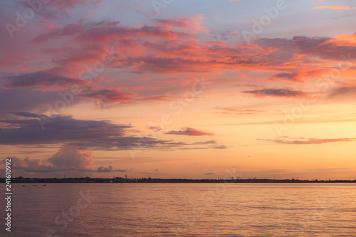 Colourful orange and pink sunset with bright sky and beautiful clouds over Baltic sea.