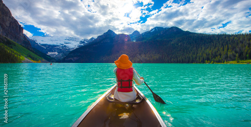 A woman in red life jacket canoeing in Lake Louise with torquoise lake and bluesky photo