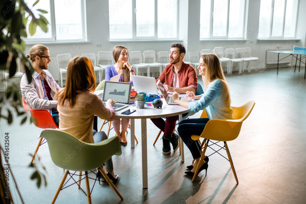 © rh2010 - Team of a young coworkers dressed casually working together with laptops sitting at the round table in the office © rh2010 - Team of a young coworkers dressed casually working together with laptops sitting at the round table in the office