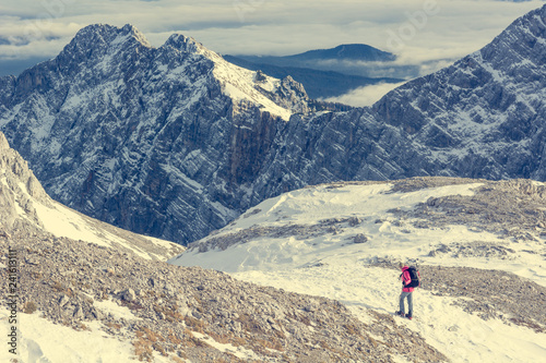 Female alpinist descending into mountain valley crossing flakes of snow. © anzebizjan