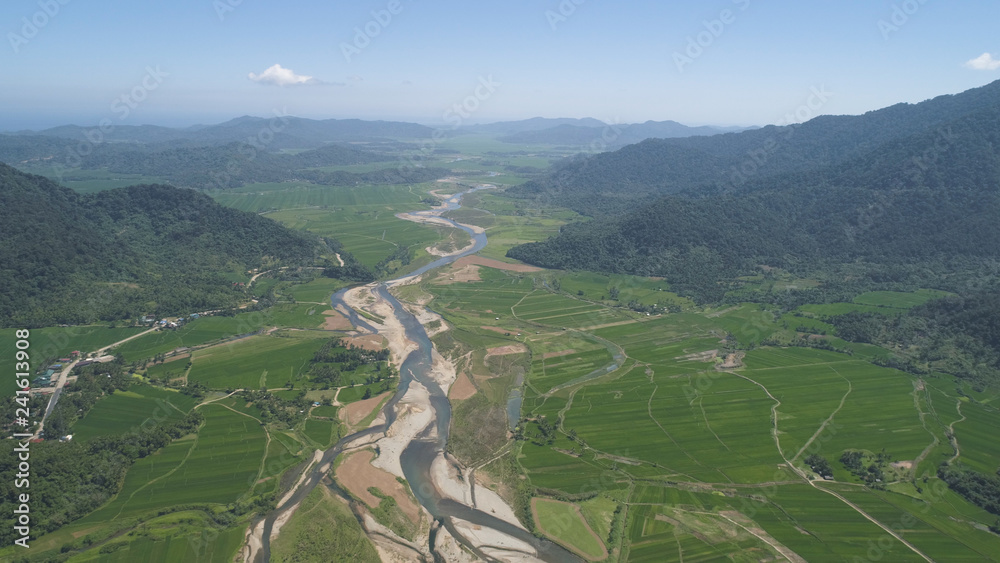Mountain valley with river, farmland, rice fields. Aerial view of Mountains with green tropical rainforest, trees, jungle with blue sky. Philippines, Luzon.