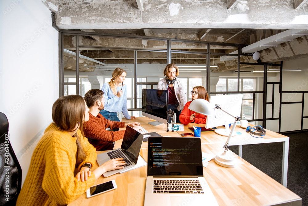 Team of a young programmers dressed casually working on computer code ...