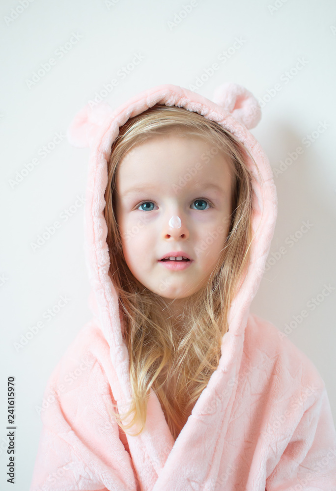 Little young girl applying moisturizing cream on her face. Skin care and beauty concept Little young girl applying moisturizing cream on her face. Skin care and beauty concept