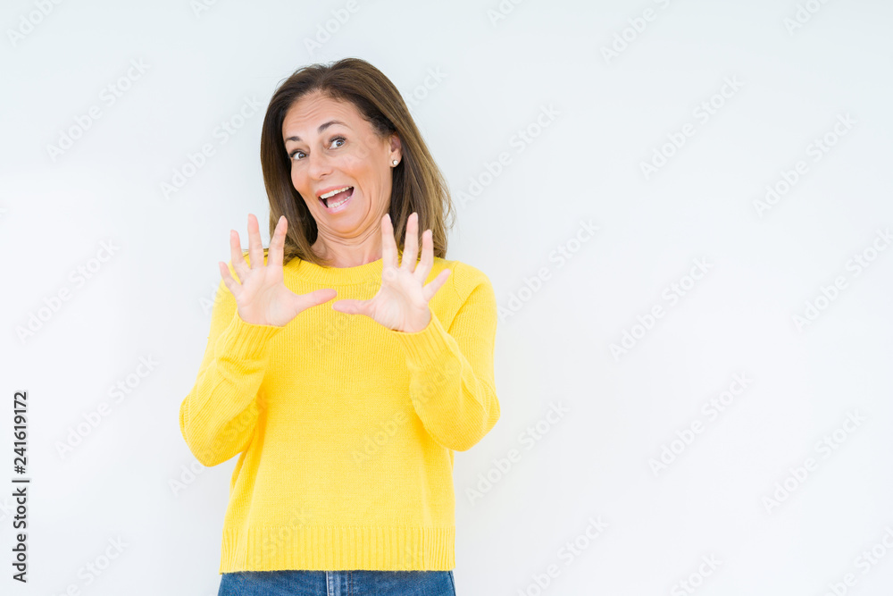 Beautiful middle age woman wearing yellow sweater over isolated background afraid and terrified with fear expression stop gesture with hands, shouting in shock. Panic concept. Beautiful middle age woman wearing yellow sweater over isolated background afraid and terrified with fear expression stop gesture with hands, shouting in shock. Panic concept.