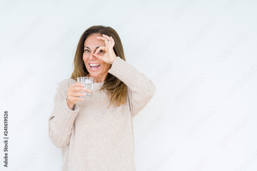 Middle age woman drinking glass of water isolated background with happy face smiling doing ok sign with hand on eye looking through fingers Middle age woman drinking glass of water isolated background with happy face smiling doing ok sign with hand on eye looking through fingers