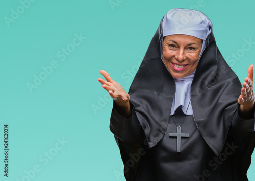 Middle age senior christian catholic nun woman over isolated background looking at the camera smiling with open arms for hug. Cheerful expression embracing happiness.