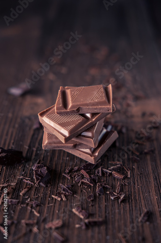 Column of dark or bitter or milk chocolate on a wood background.