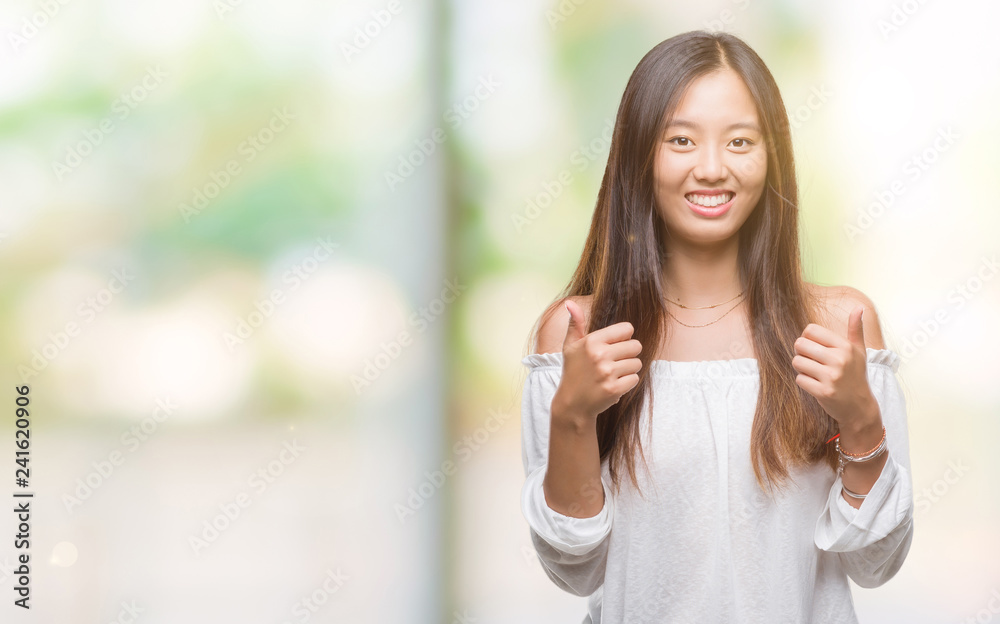 Young asian woman over isolated background success sign doing positive gesture with hand, thumbs up smiling and happy. Looking at the camera with cheerful expression, winner gesture. Young asian woman over isolated background success sign doing positive gesture with hand, thumbs up smiling and happy. Looking at the camera with cheerful expression, winner gesture.