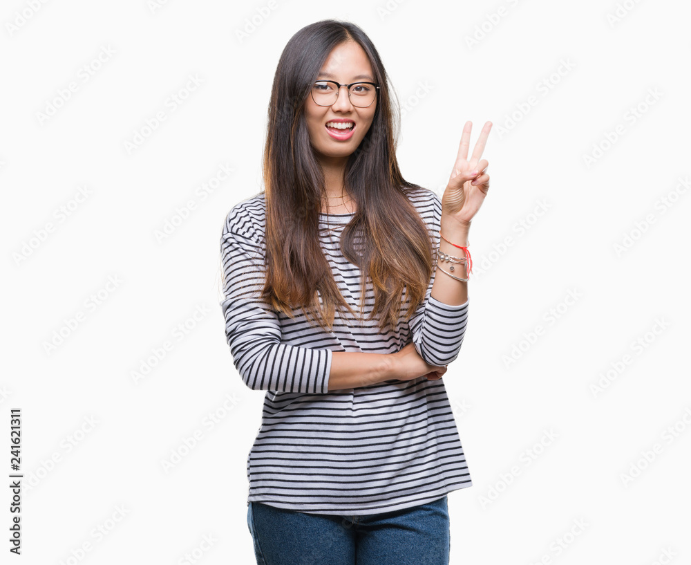 Young asian woman wearing glasses over isolated background smiling with happy face winking at the camera doing victory sign. Number two. Young asian woman wearing glasses over isolated background smiling with happy face winking at the camera doing victory sign. Number two.