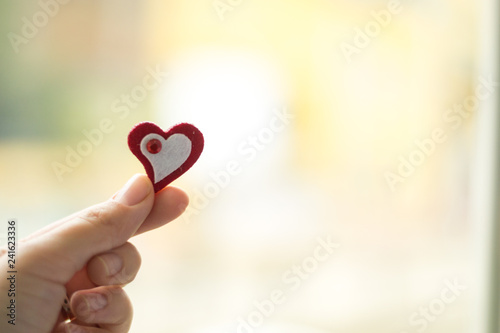 Close up red and white color heart with gem in hand on warm background. Copy space for text. Healthy lifestyle concept.
