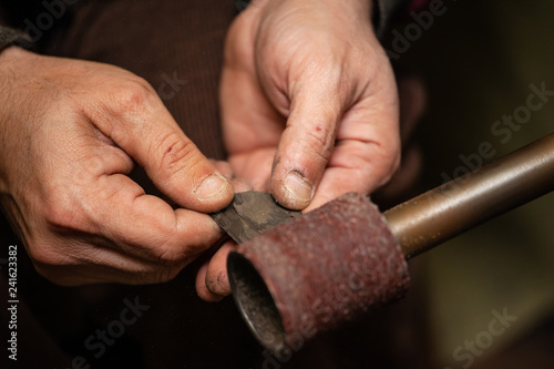 close-up of male hands of a worker grinding a part on a machine