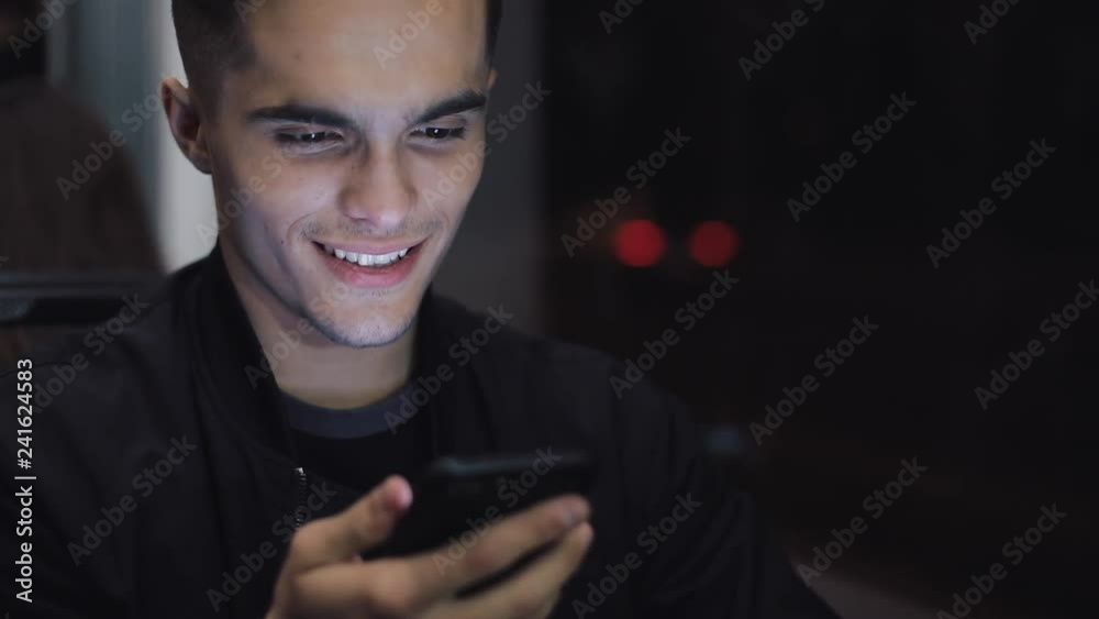 Happy young man using smartphone while riding tram, steadicam shot. Slow motion