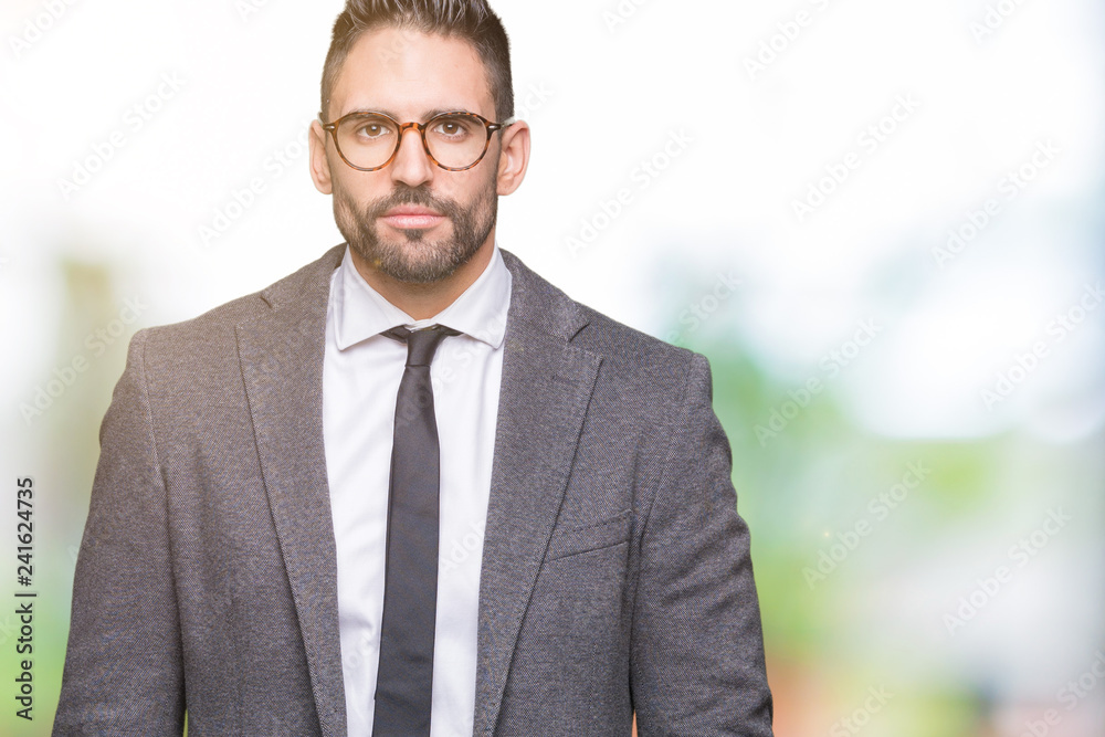Young handsome business man over isolated background Relaxed with serious expression on face. Simple and natural looking at the camera.