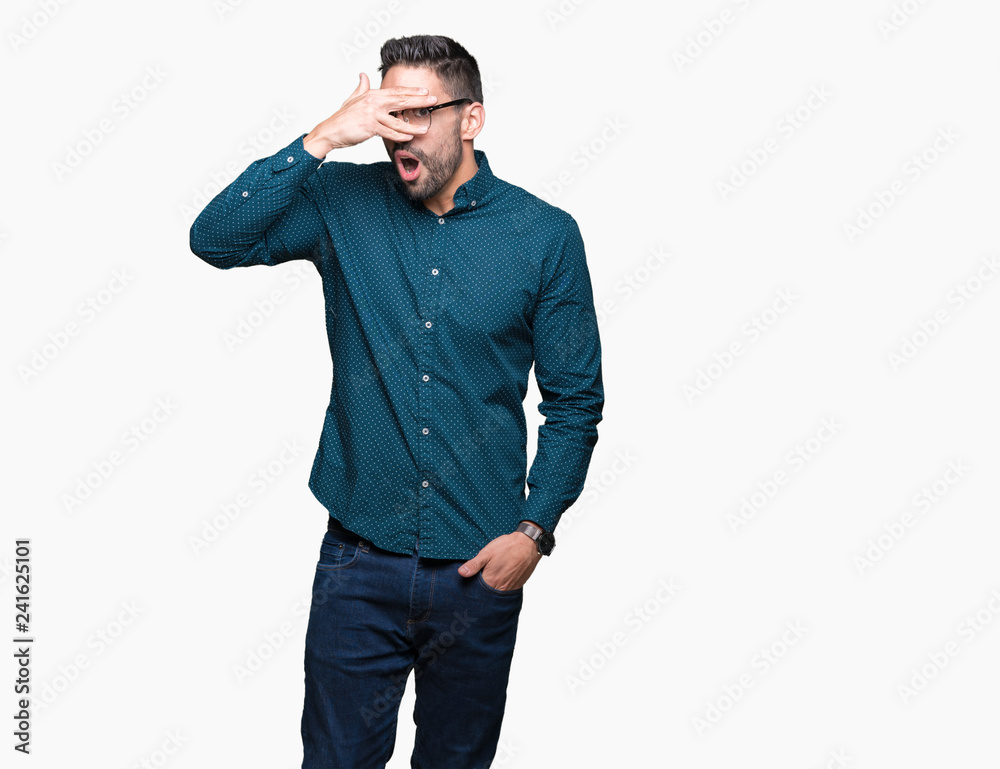 Young handsome business man wearing glasses over isolated background peeking in shock covering face and eyes with hand, looking through fingers with embarrassed expression. Young handsome business man wearing glasses over isolated background peeking in shock covering face and eyes with hand, looking through fingers with embarrassed expression.