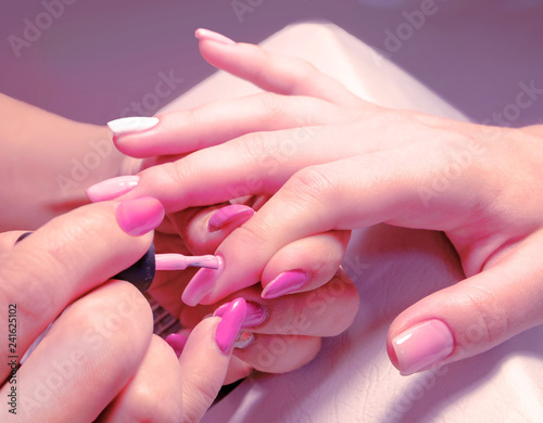 Hands of a girl doing a modern manicure on a purple background.