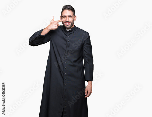 Young Christian priest over isolated background Pointing with hand finger to face and nose, smiling cheerful