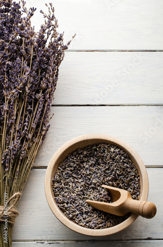 Fototapeta Naklejka Na Ścianę i Meble -  Tied Dried Lavender Flowers with Bowl of Buds on White Planked Wooden Table from Above