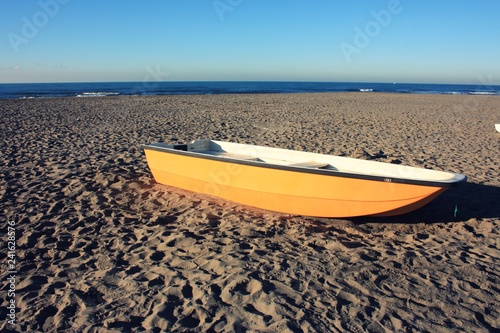 small abandoned fishing yellow boat on a deserted sandy beach in a sunny winter day. © Alessia