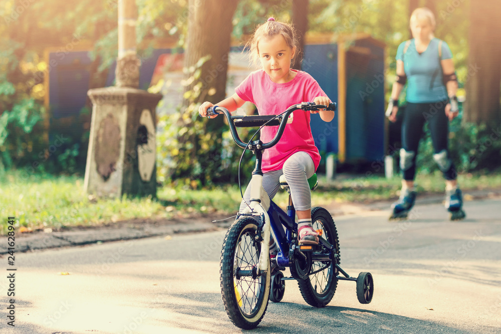 Little girl with helmet riding bike at sunset