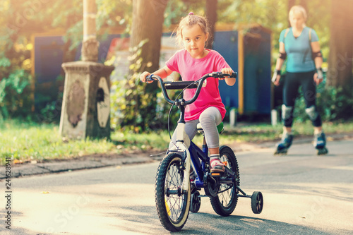 Little girl with helmet riding bike at sunset
